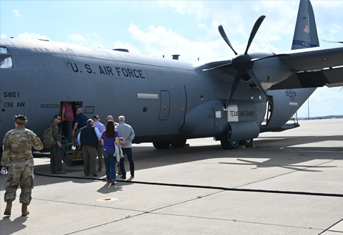 A group of people posing in front of a C-130J Super Hercules military transport aircraft