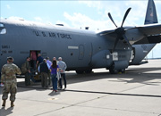 A group of people posing in front of a C-130J Super Hercules military transport aircraft